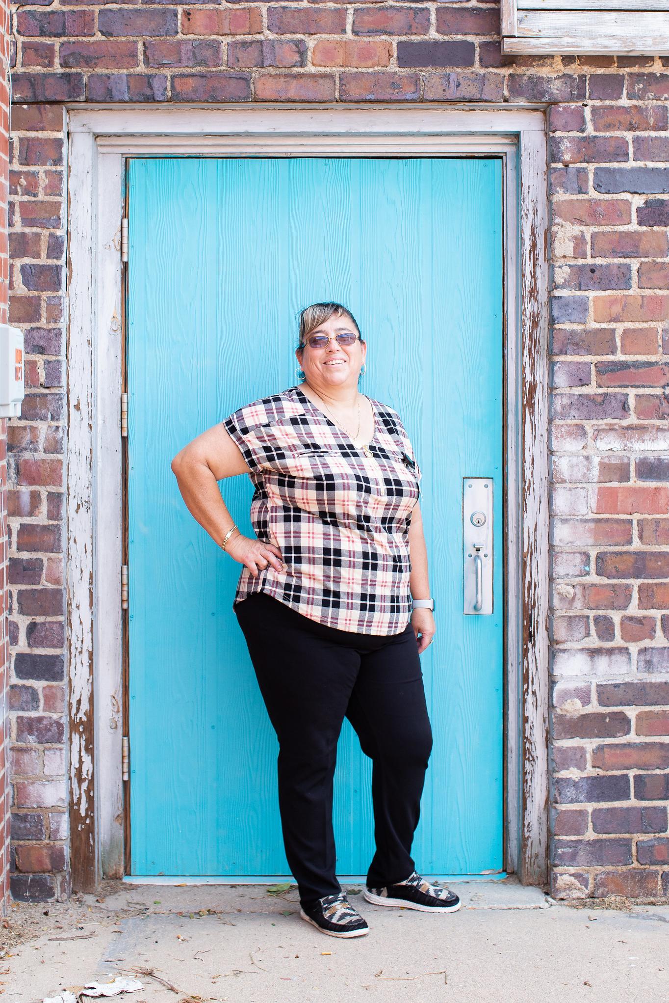 Student poses for a photo against a blue door