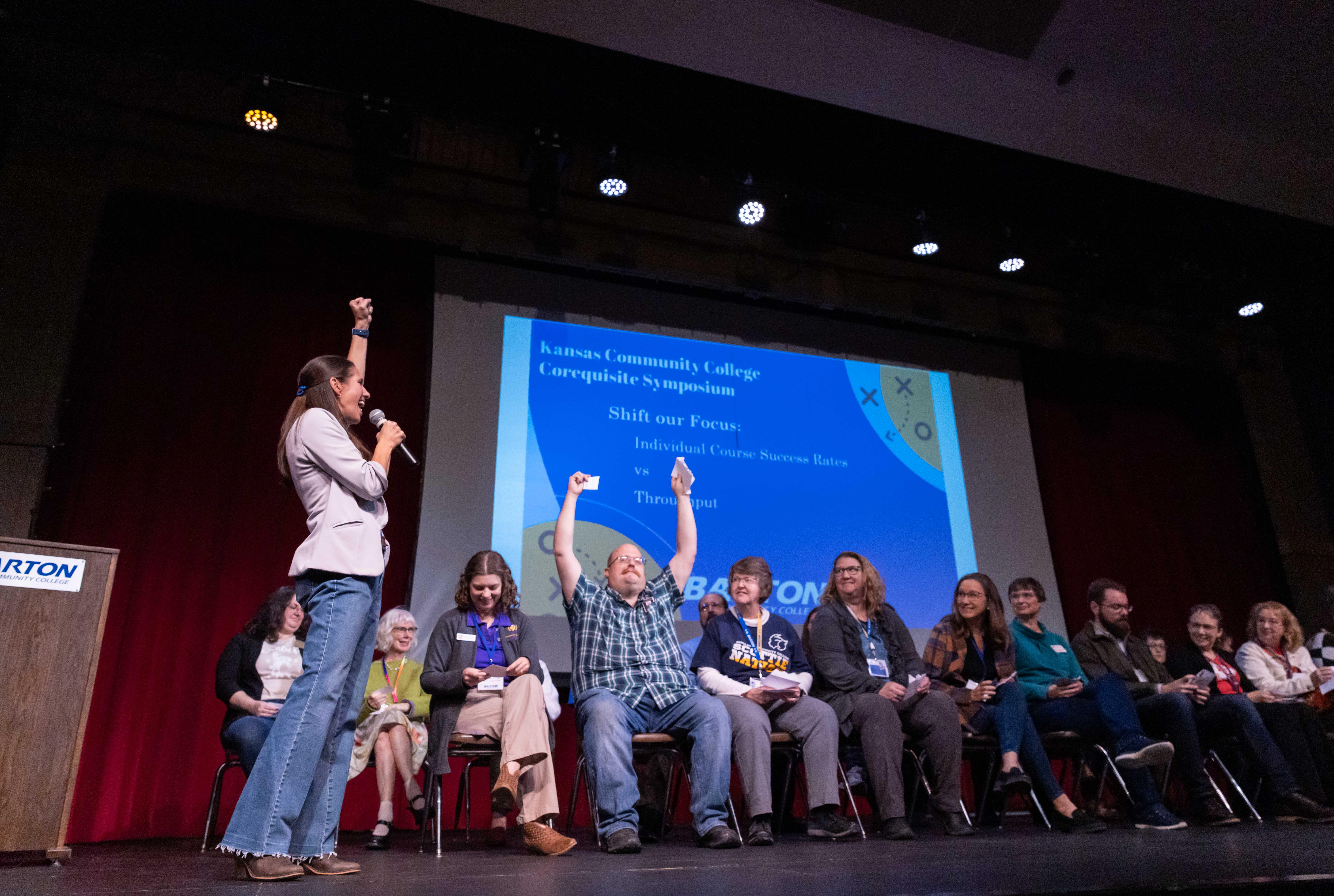 people raising their hands in excitement on a stage full of people
