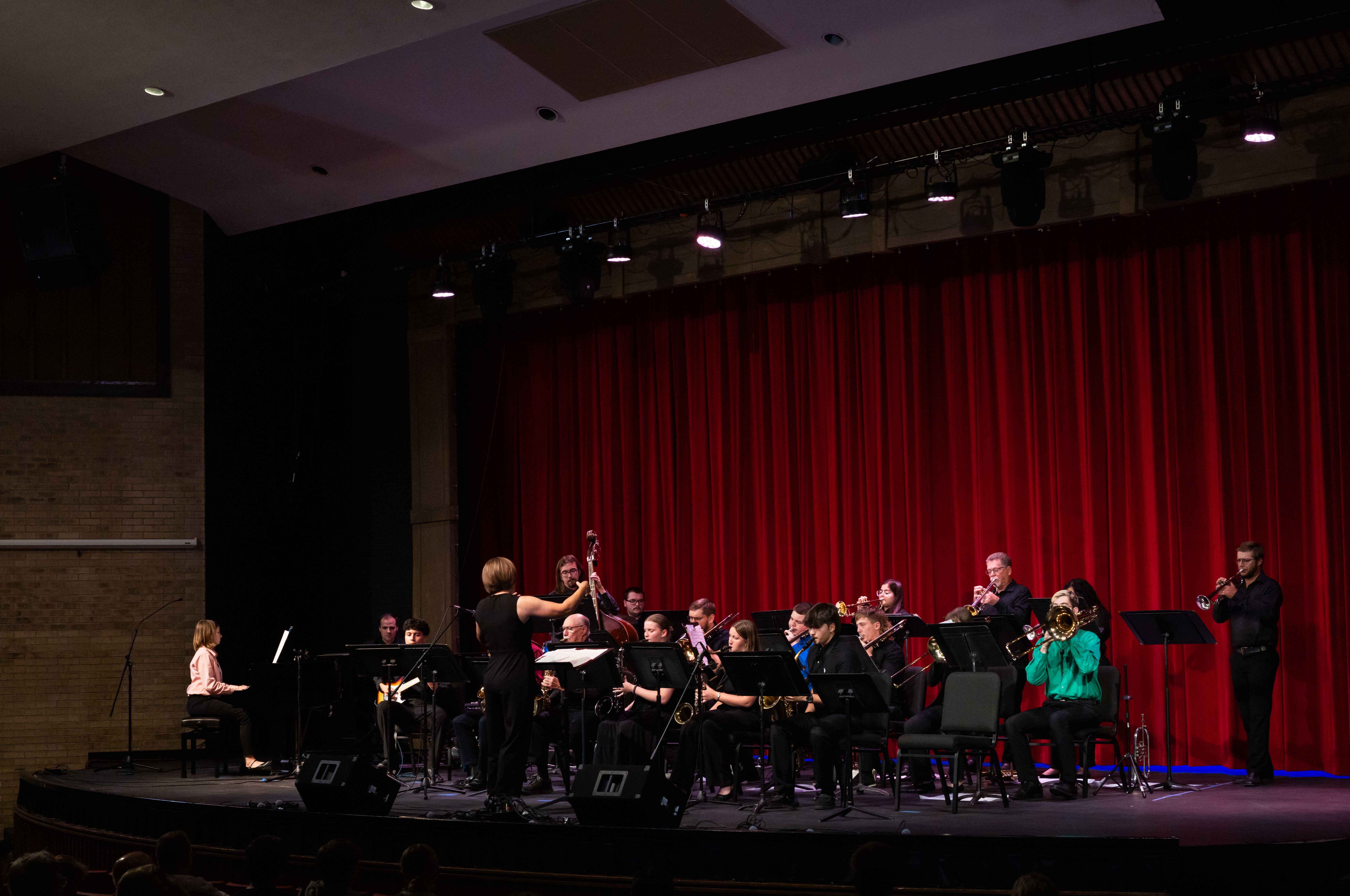 musicians performing on a stage with a red curtain in background