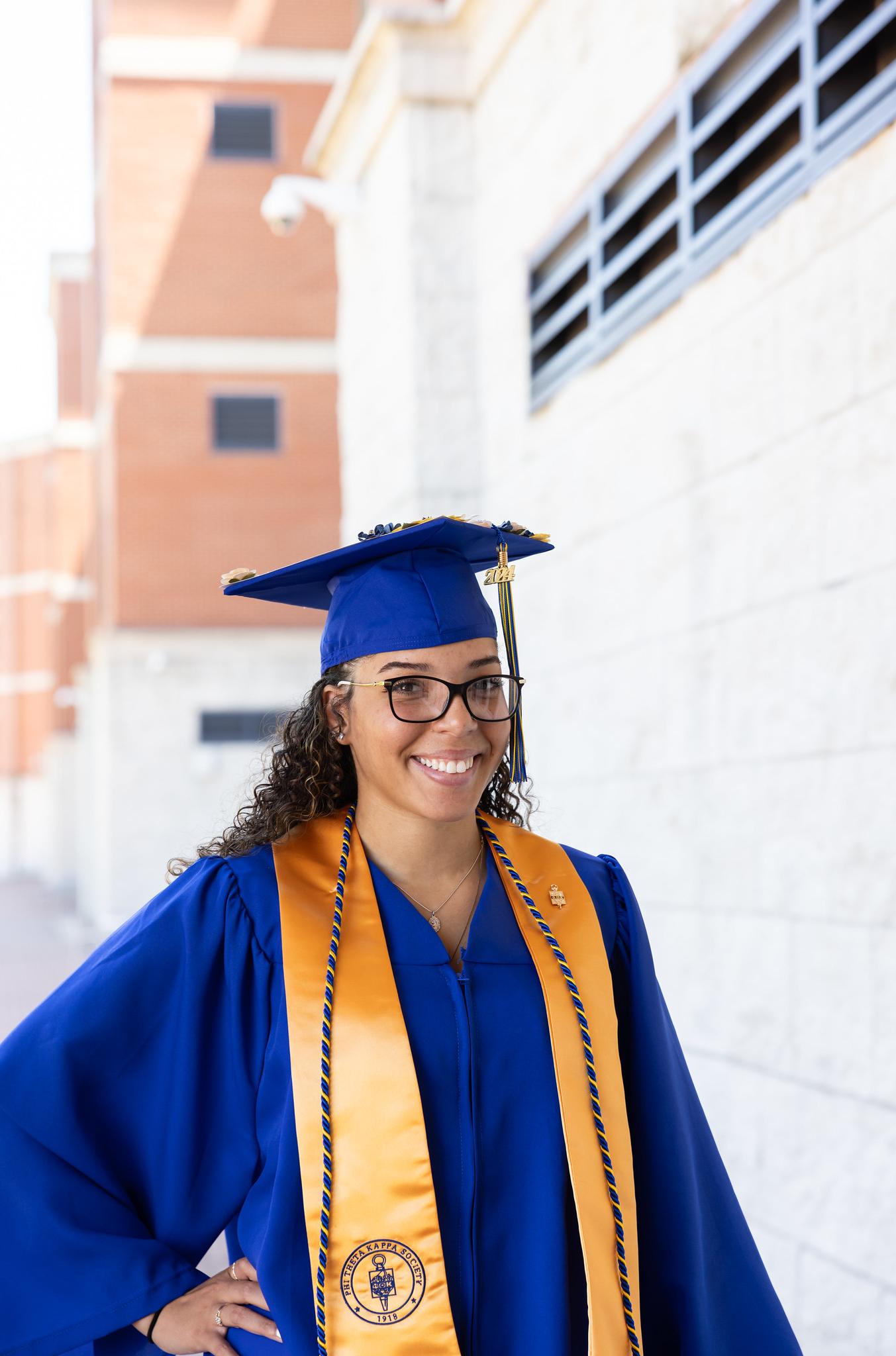 graduate in blue gown smiling