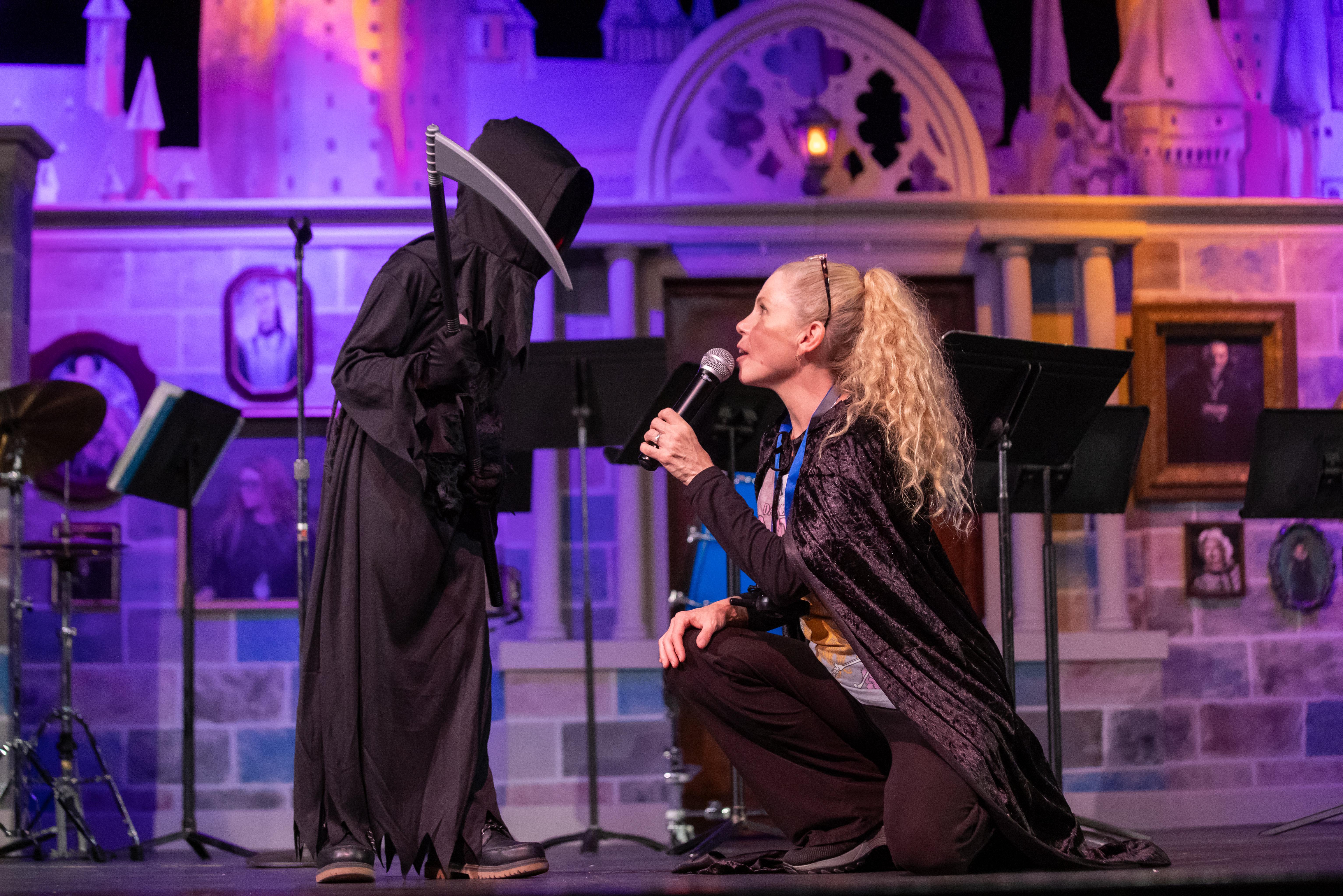 woman w a microphone talks to a kid in costume at a costume contest