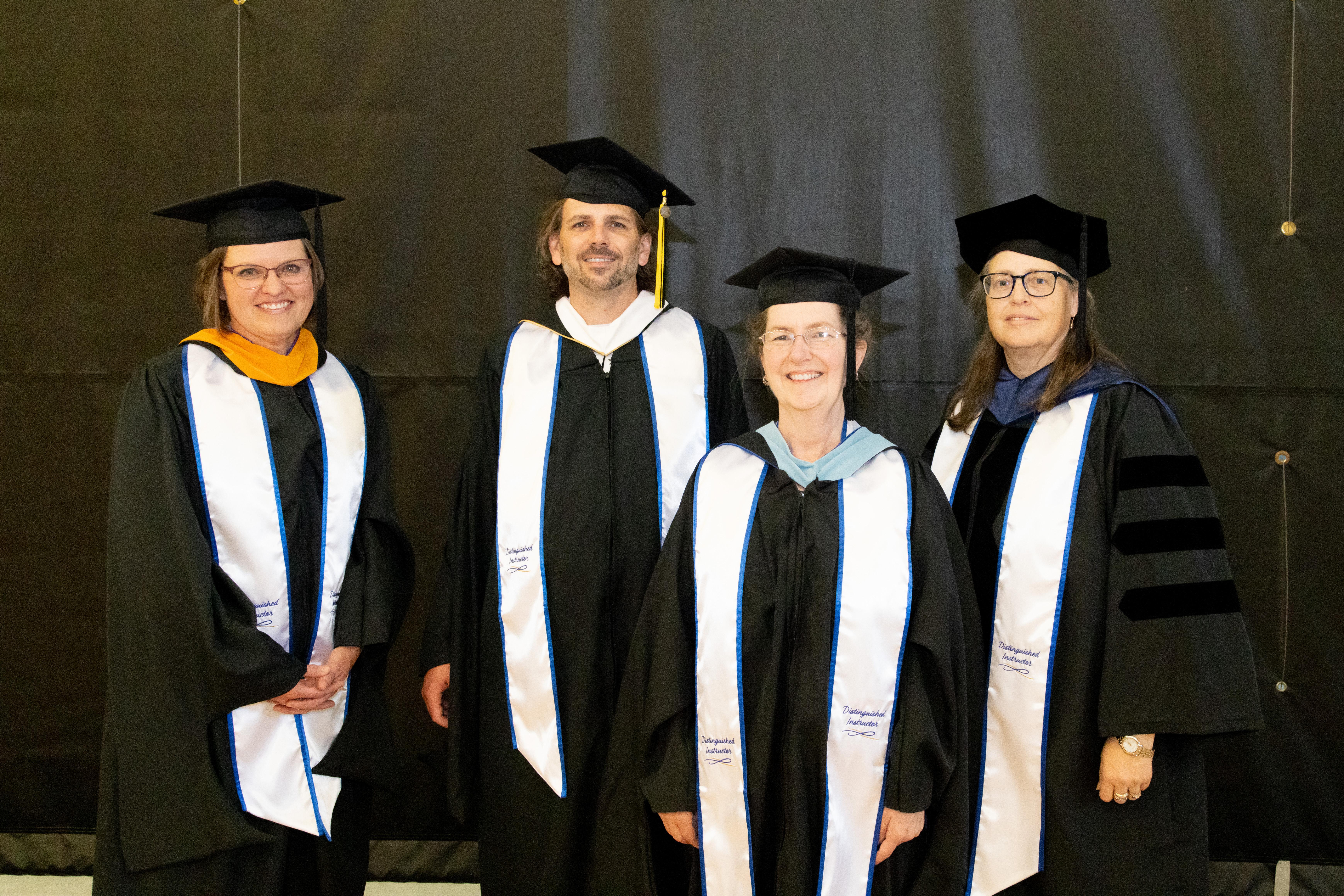 Barton Community College 2025 Distinguished Instructors (left to right) Heidi McKennon, Justin Brown, Stephenie Bradford-Clark, and Ann Ingala pose for a photo before the Barton commencement ceremony Friday night in the Barton Gymnasium. (Not pictured, Amber Bebout.)