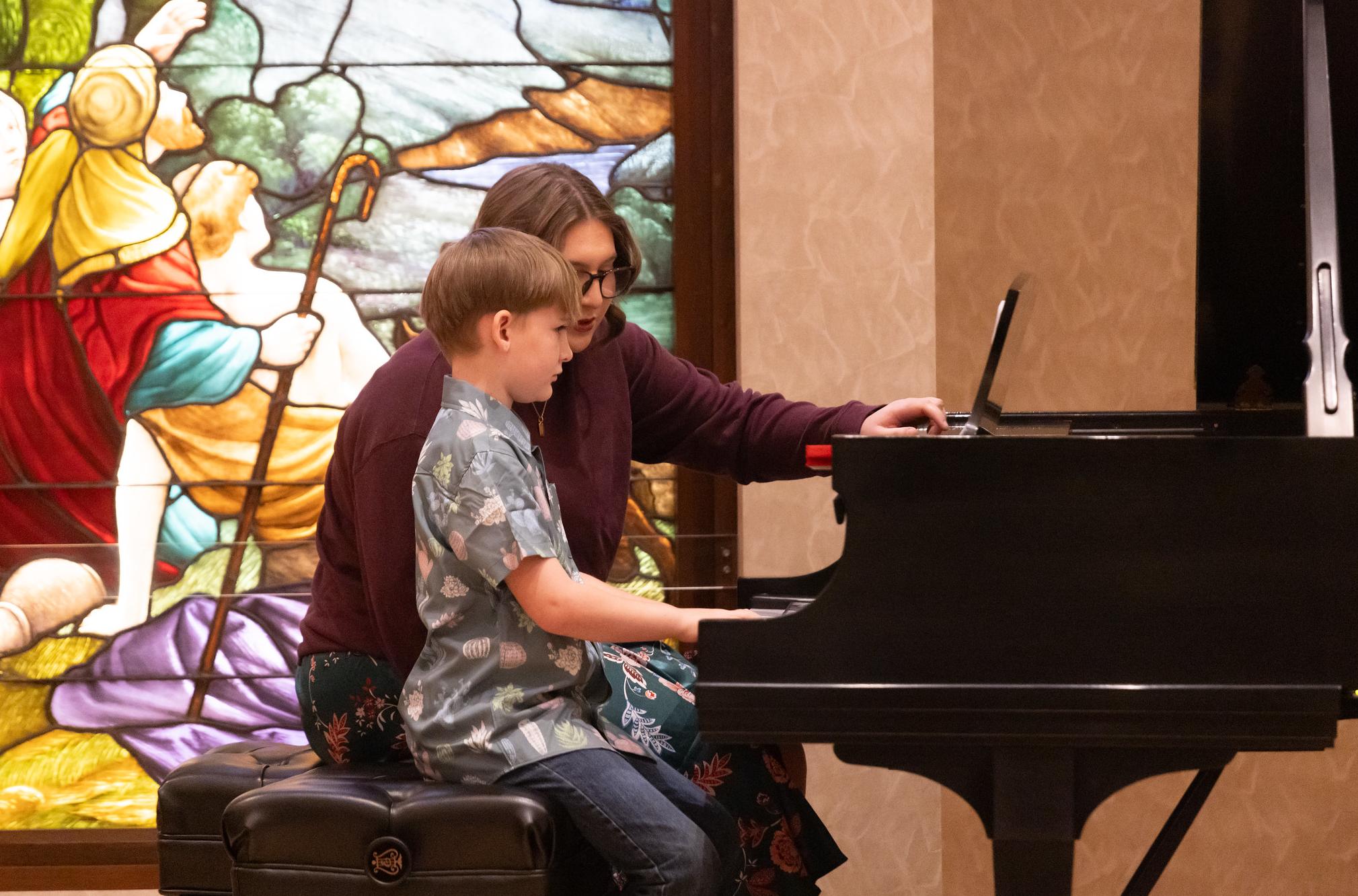 college student teaching a young child piano