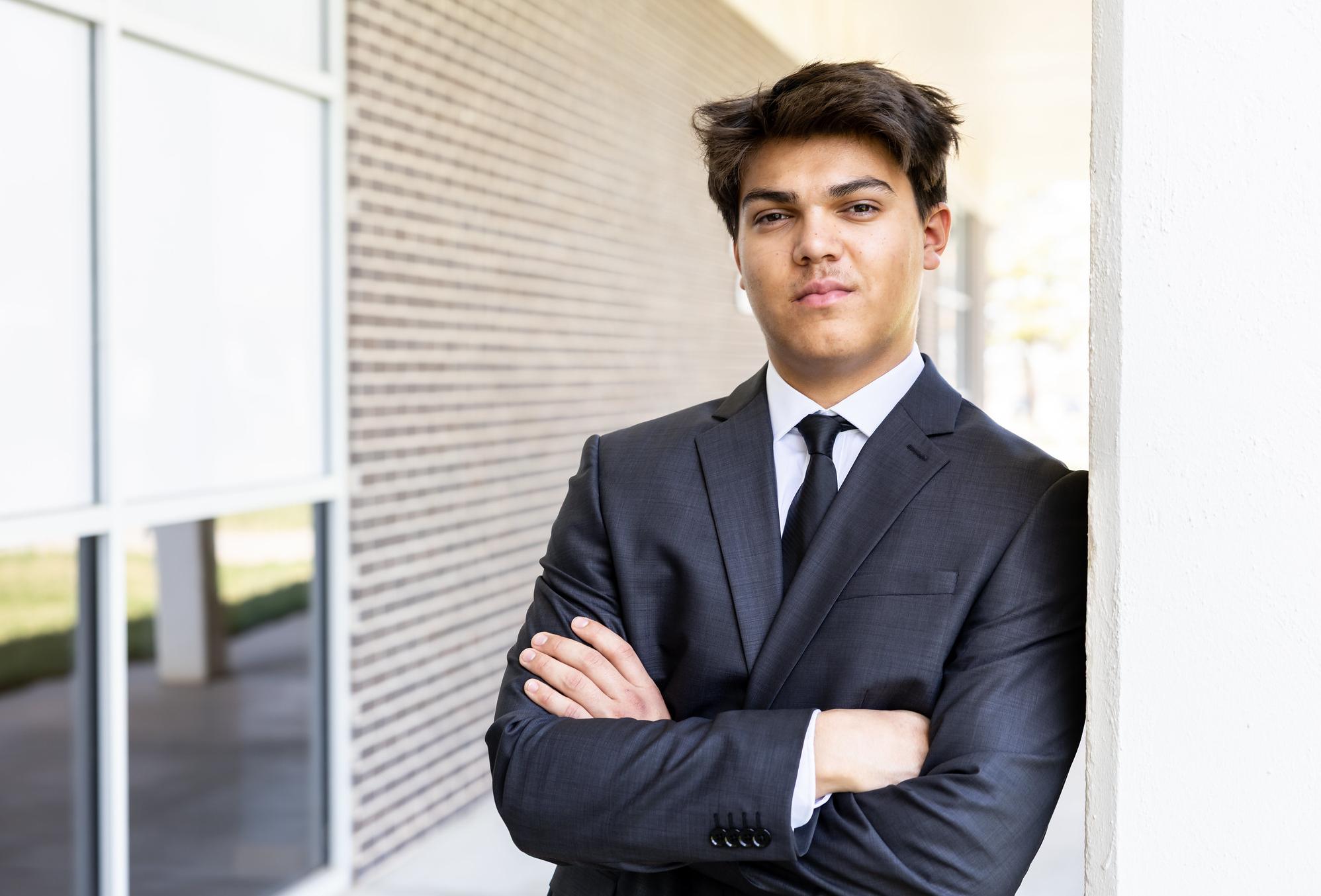 young man standing in a suit with arms crossed