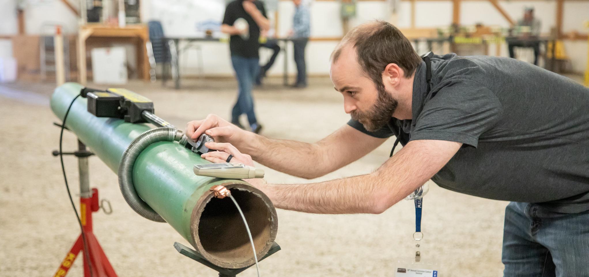 Corrosion conference attendee checks pipe and controls