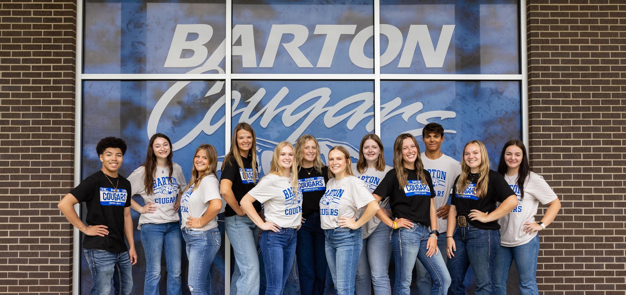 Student ambassadors smile in front of Barton Cougars window