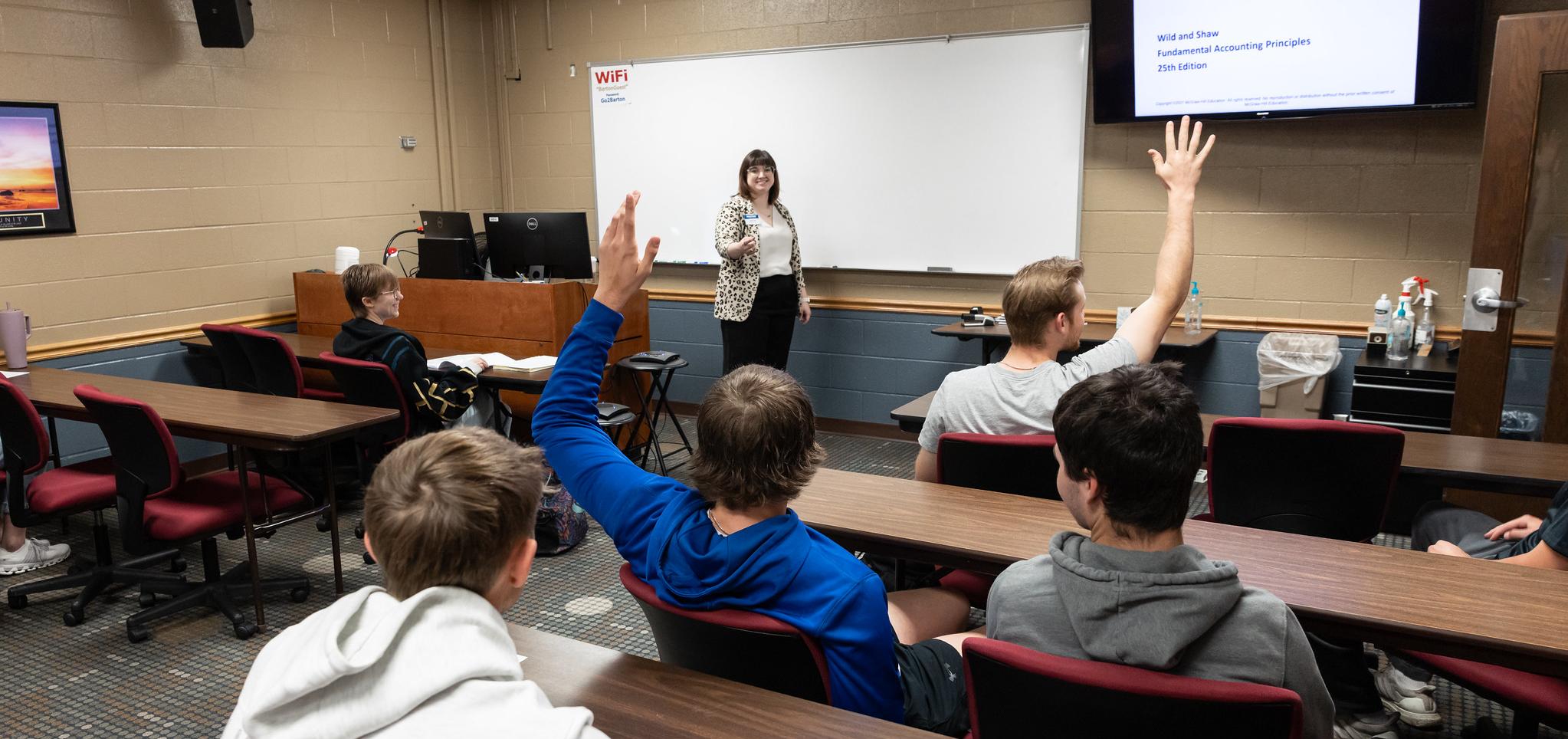 Students raise hands in classroom