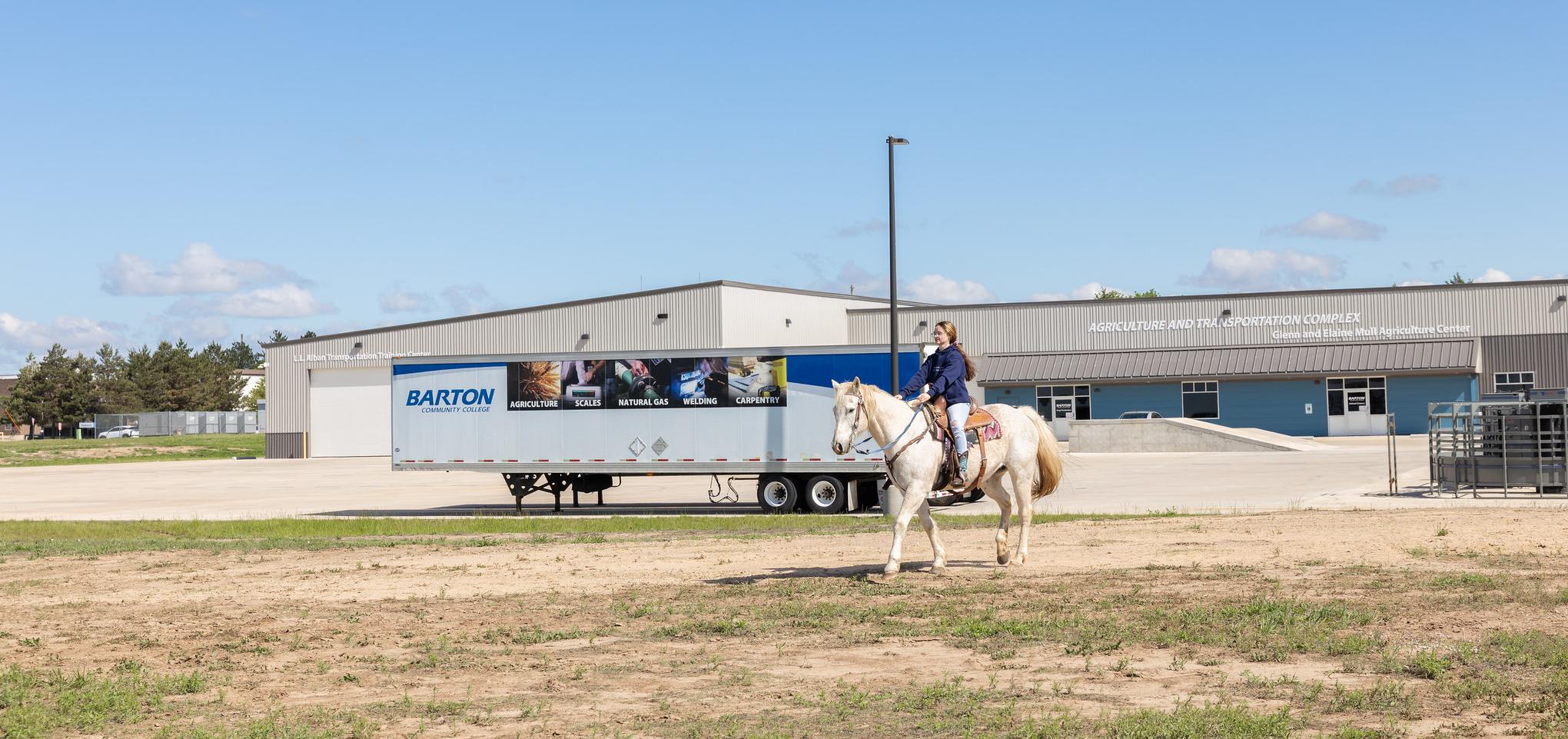 Barton student rides horse outside Barton Ag Complex