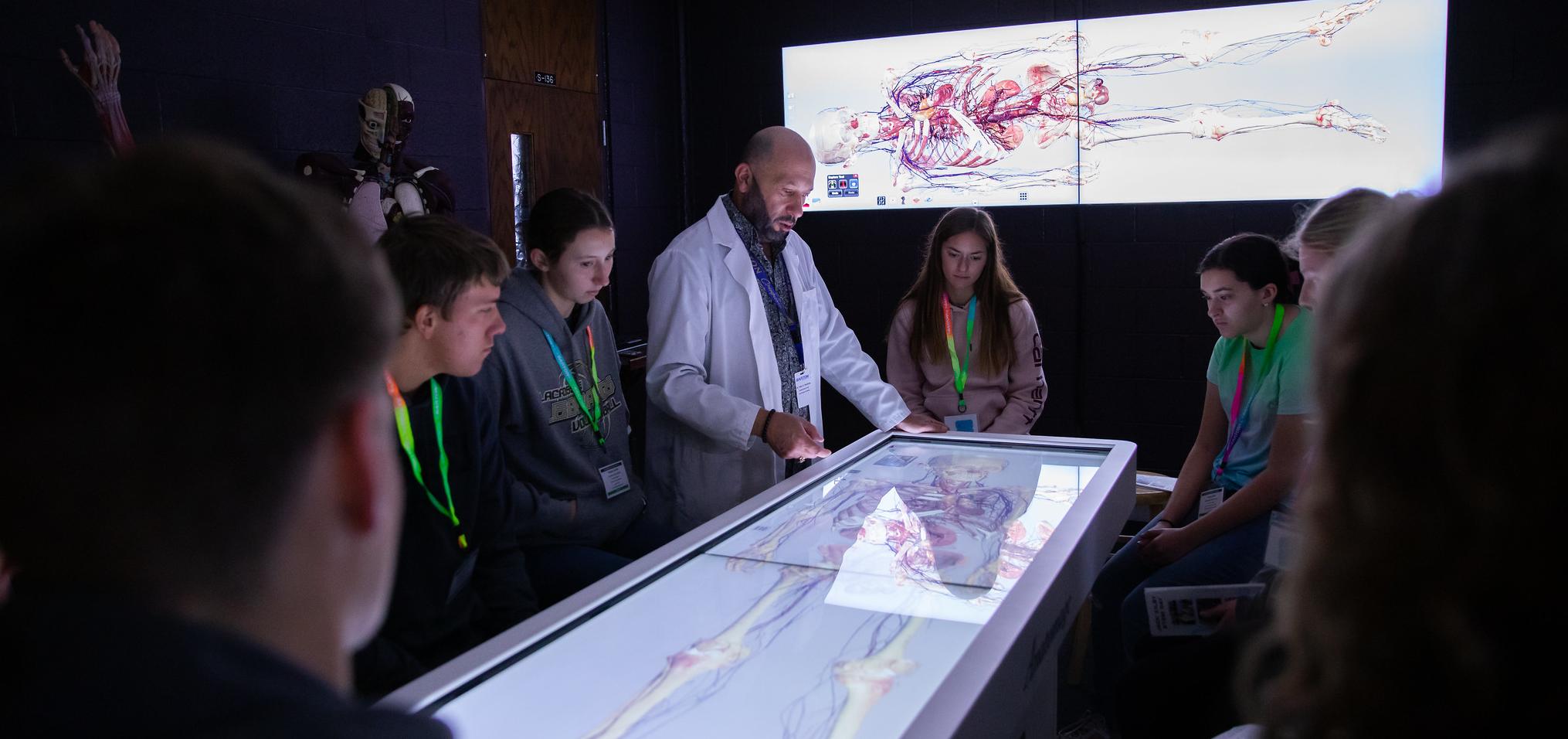 Professor stands at anatomage table with students