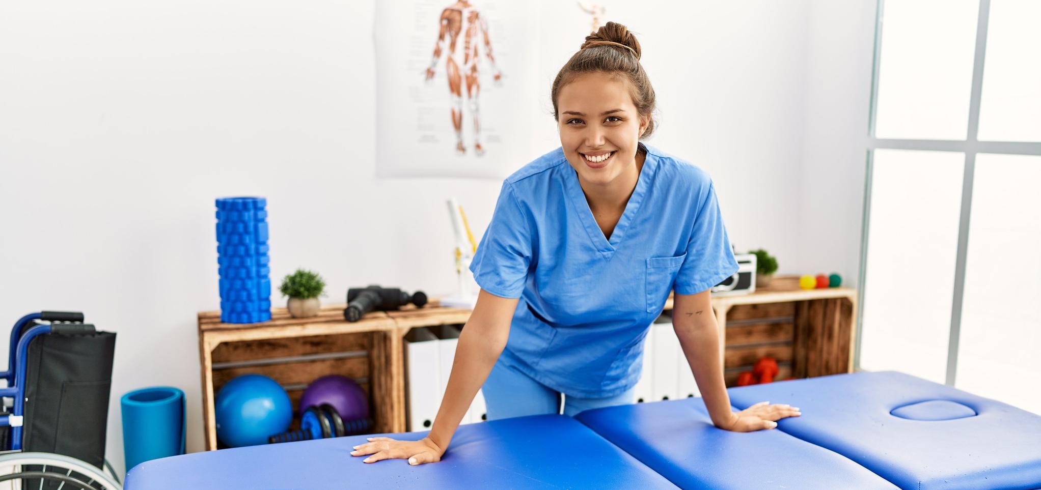 Physical Therapy assistant stands at physical therapy table