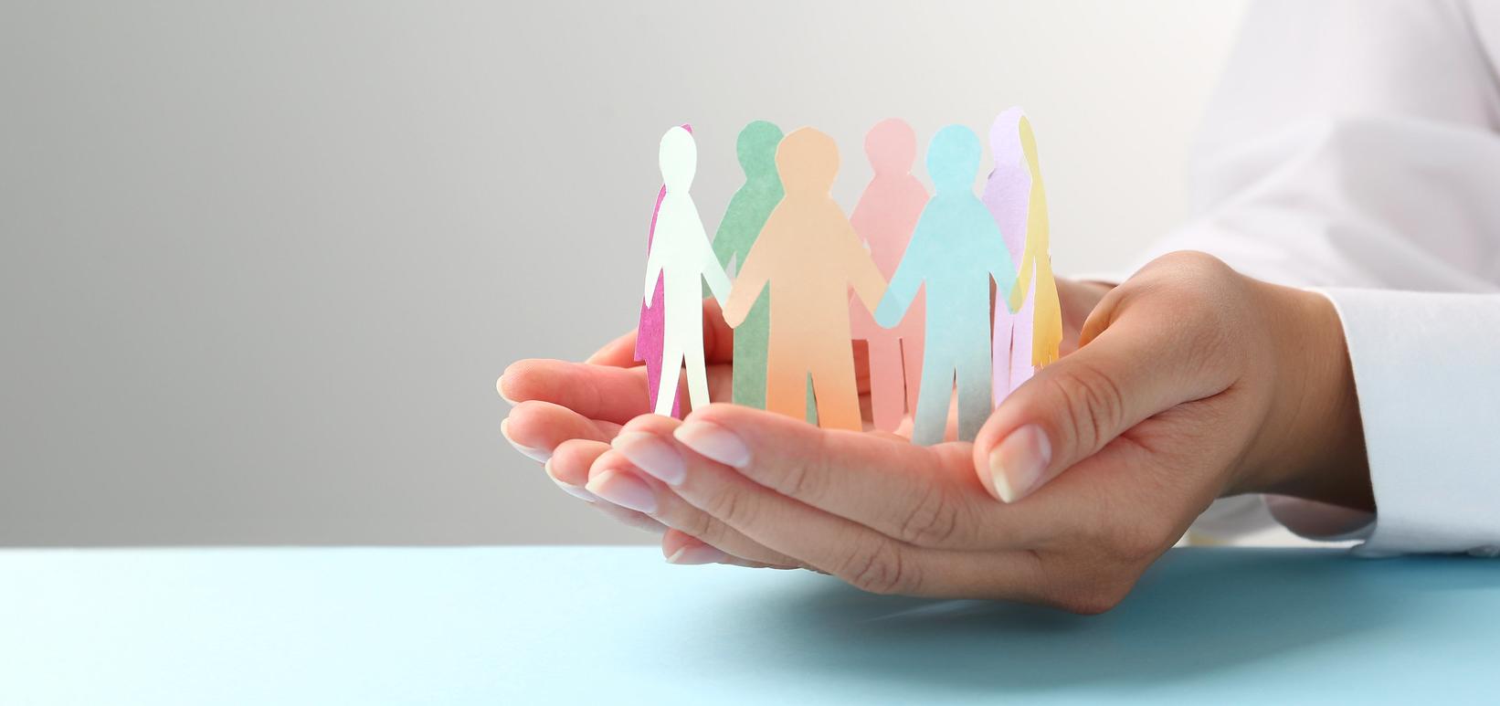 hands hold cutout shapes of humans holding hands