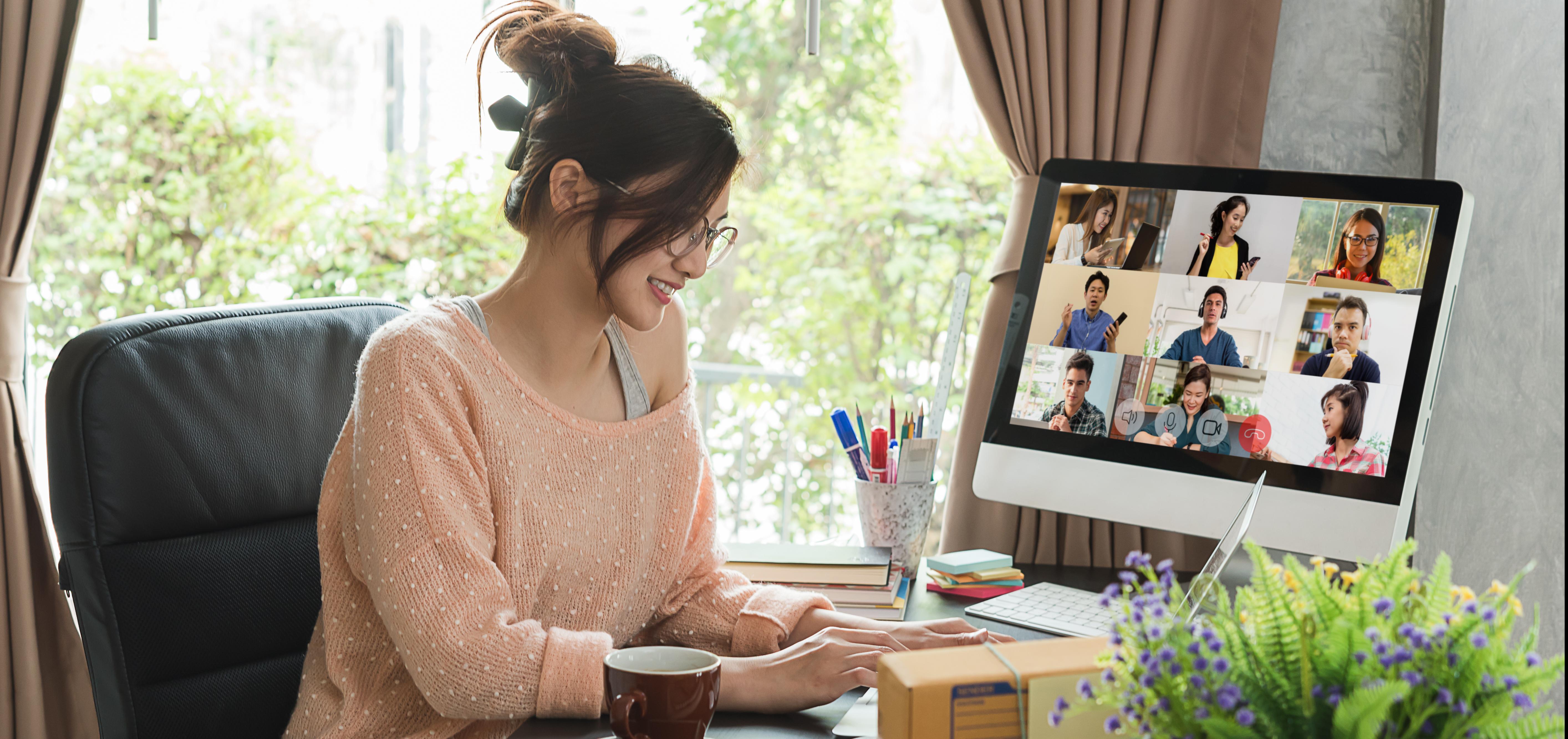 Woman works remotely with coworkers on computer screen